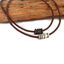 two-brown-leather-silver-cylinder-black-hex-nut-necklaces-against-wood-white-background