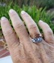   hammered copper cuff ring with blue crystals on ring finger in the garden
