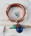 Handcrafted artisan copper cuff ring with blue gemstone on white distressed background