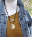 Mannequin with jean jacket wearing layered brass and black artisan necklaces