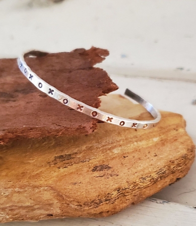silver XOX bracelet on rocks
