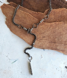 Black gunmetal chain silver stone Y necklace on white table with wood