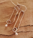 Long oval cooper loop and silver earrings on wood
