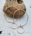 Hammered silver big hoop little hoop earrings against rock
