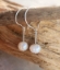silver hoop white pearl earring on stick against wood background