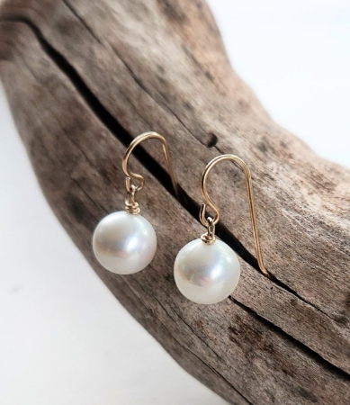 big white singular pearls earrings with gold ear wire on wood branch