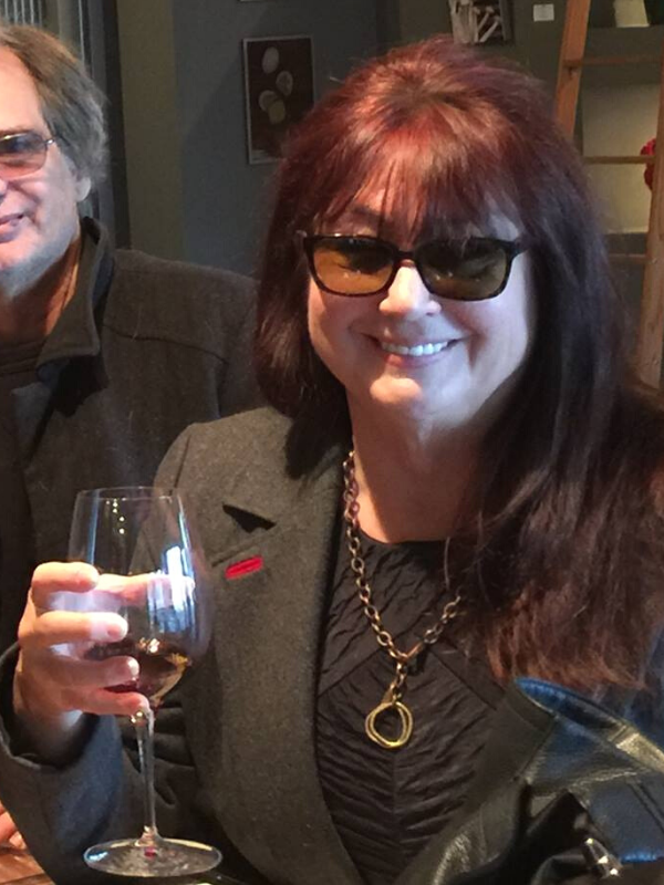 wearing a chunky metal handcrafted necklace and a glass of wine