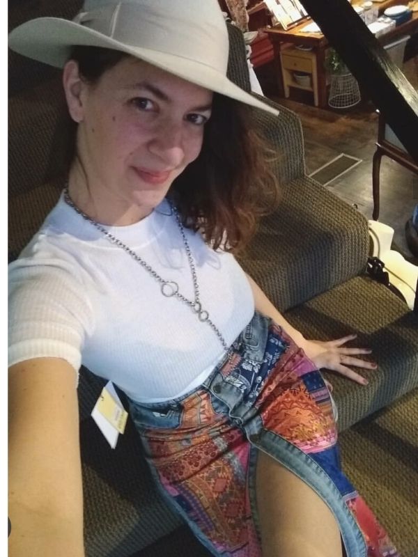 model wearing long funky silver necklace with denim skirt