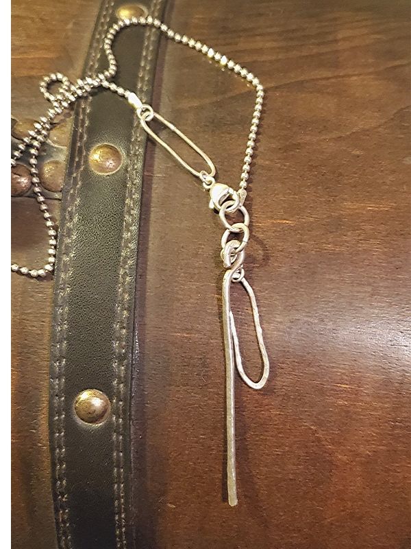 silver artisan necklace on wood trunk