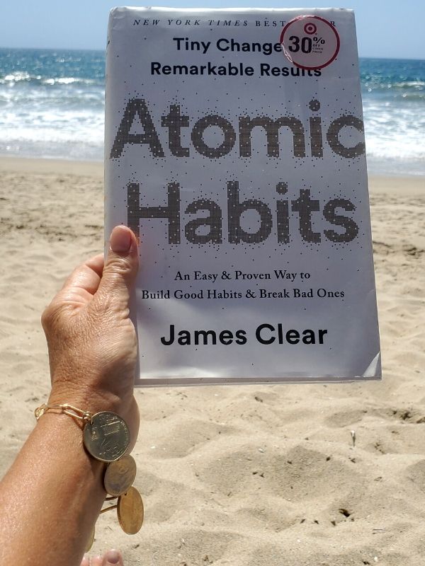 at beach with book and coin bracelet