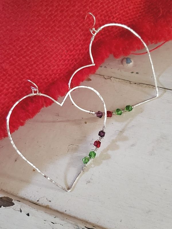 silver birthstone heart earrings on red pillow