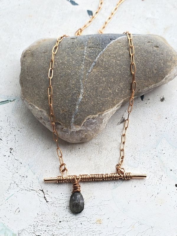 gray gemstone bronze bar necklace on gray stone