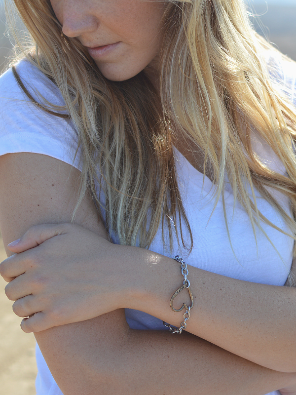 female white shirt with chain bracelet on folded arms