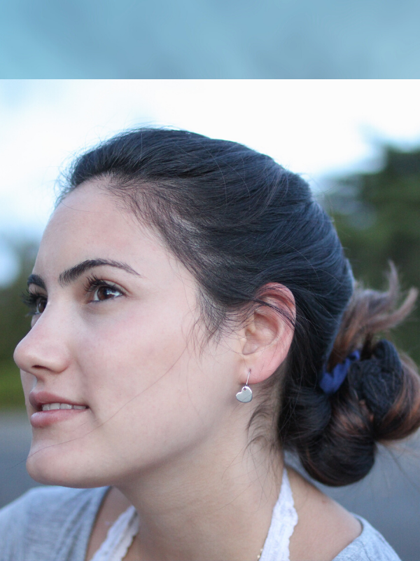 petite silver heart earrings on model with hair in bun